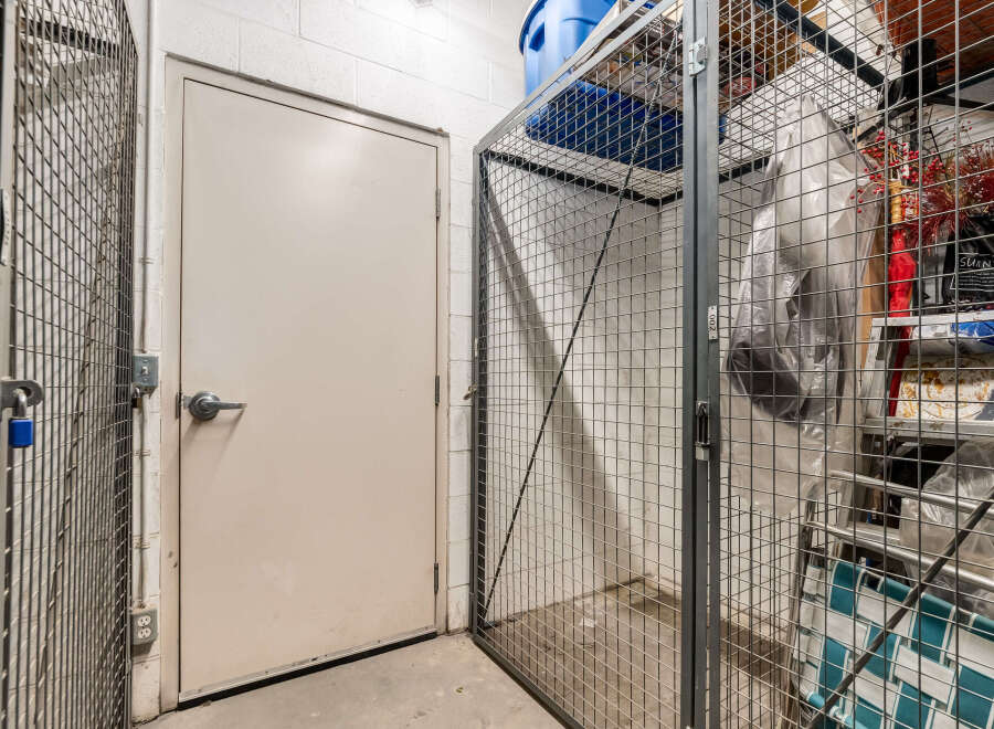 Secure your belongings in this spacious storage unit, featuring a sturdy metal cage with a padlock for added security.