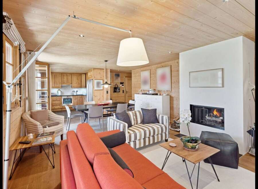 Experience cozy living in this charming mountain retreat, featuring a warm wood-paneled interior and a modern fireplace.
