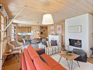 Experience cozy living in this charming mountain retreat, featuring a warm wood-paneled interior and a modern fireplace.