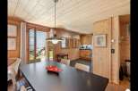 Experience cozy living in this charming wooden cabin, featuring a spacious dining area with a dark wood table and comfortable seating.