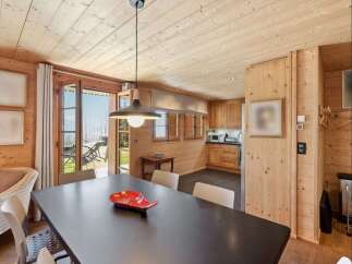 Experience cozy living in this charming wooden cabin, featuring a spacious dining area with a dark wood table and comfortable seating.