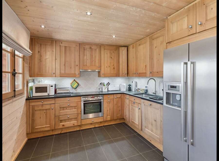 This charming kitchen features warm, natural wood cabinetry and a coordinating wooden ceiling, creating a cozy and inviting atmosphere.