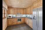This charming kitchen features warm, natural wood cabinetry and a coordinating wooden ceiling, creating a cozy and inviting atmosphere.