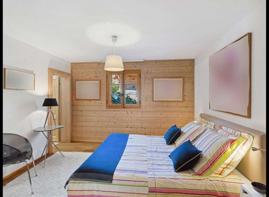 Experience cozy mountain living in this charming bedroom featuring a comfortable bed with striped linens and plush blue pillows.