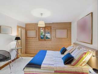 Experience cozy mountain living in this charming bedroom featuring a comfortable bed with striped linens and plush blue pillows.