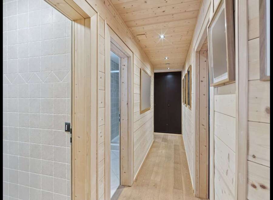 Step into this charming hallway featuring warm, natural wood paneling on the walls and ceiling, creating a cozy and inviting atmosphere.