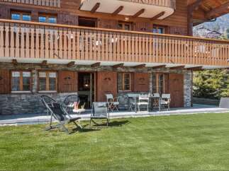 Experience alpine charm with this stunning property featuring a rustic wooden facade and stone accents.