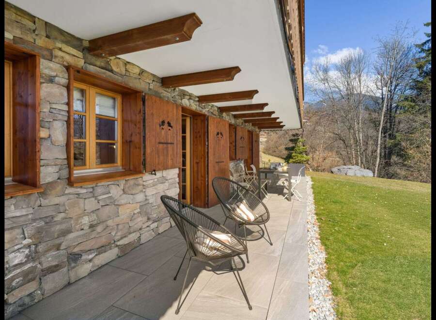 Experience alpine charm with this property featuring a rustic stone facade and traditional wooden shutters.