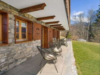 Experience alpine charm with this property featuring a rustic stone facade and traditional wooden shutters.