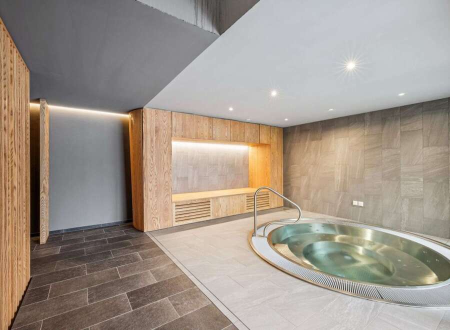 Experience ultimate relaxation in this modern spa area, featuring a luxurious jacuzzi and elegant wooden accents.
