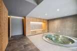 Experience ultimate relaxation in this modern spa area, featuring a luxurious jacuzzi and elegant wooden accents.