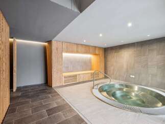 Experience ultimate relaxation in this modern spa area, featuring a luxurious jacuzzi and elegant wooden accents.