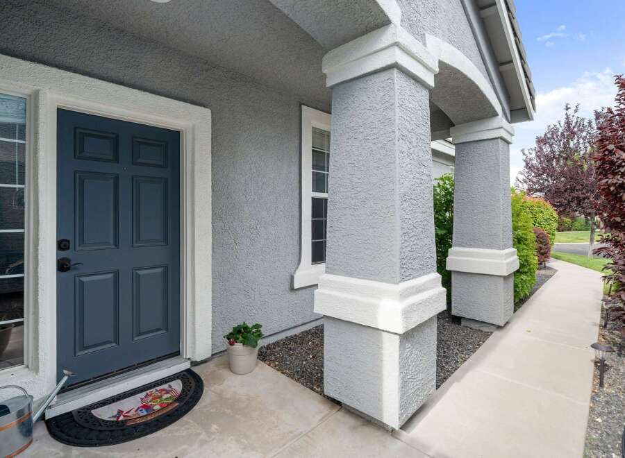 Welcome guests to your home with this charming front entrance featuring a classic blue door and a decorative doormat.