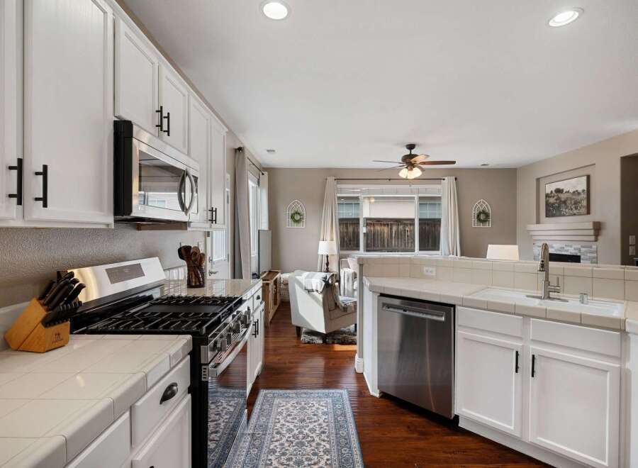 This spacious kitchen features white cabinetry, a stainless steel gas range, and a built-in microwave.