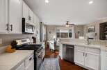 This spacious kitchen features white cabinetry, a stainless steel gas range, and a built-in microwave.