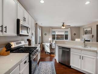 This spacious kitchen features white cabinetry, a stainless steel gas range, and a built-in microwave.