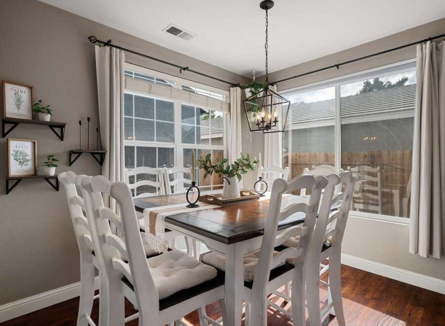 This charming dining room features a beautiful wooden table surrounded by white ladder-back chairs, perfect for family gatherings.