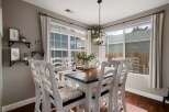 This charming dining room features a beautiful wooden table surrounded by white ladder-back chairs, perfect for family gatherings.