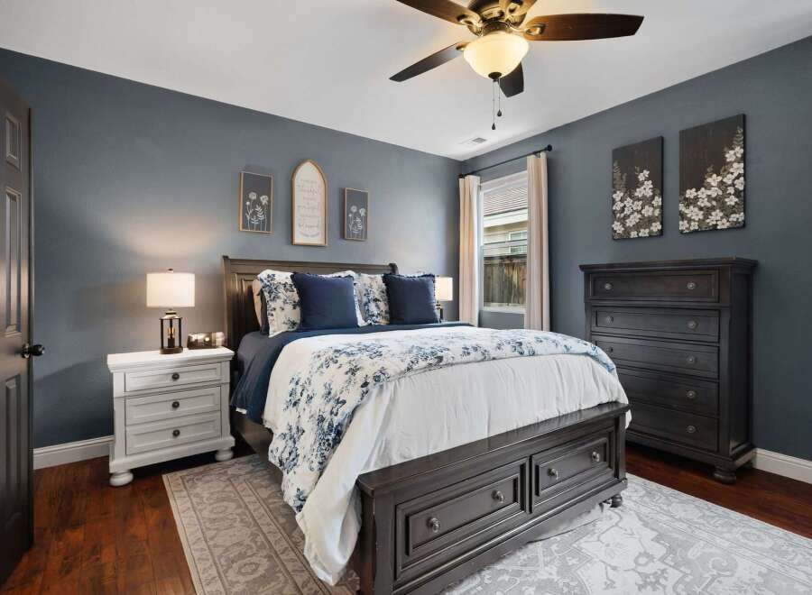 Discover this inviting bedroom featuring a dark wood bed frame with ample storage, complemented by a blue and white floral comforter.