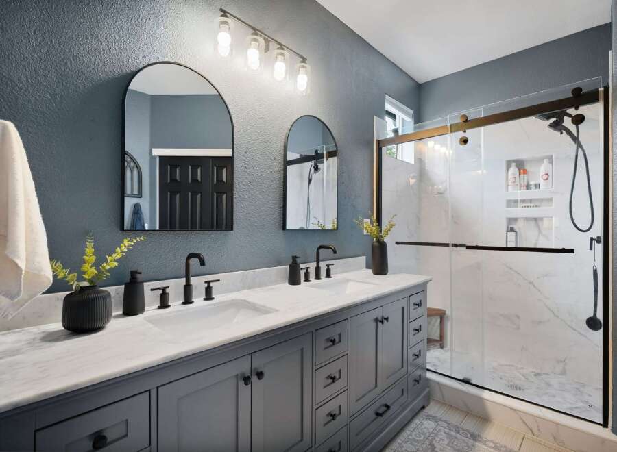 Experience luxury in this stunning bathroom featuring a spacious double vanity with marble countertops and sleek gray cabinetry.