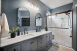 Experience luxury in this stunning bathroom featuring a spacious double vanity with marble countertops and sleek gray cabinetry.
