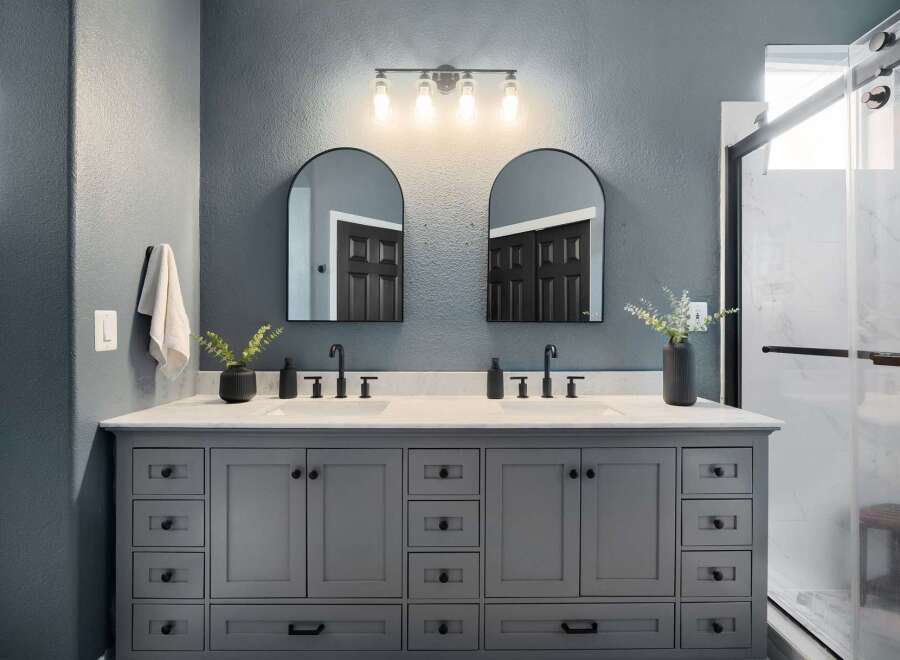 Experience luxury in this modern bathroom featuring a spacious double vanity with sleek black fixtures and ample storage.