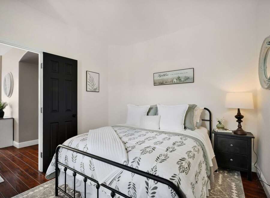 This charming bedroom features a cozy queen-size bed with a botanical-print duvet and plush white bedding.
