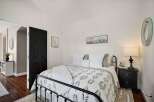 This charming bedroom features a cozy queen-size bed with a botanical-print duvet and plush white bedding.