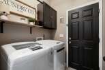 This laundry room features a white top-load washing machine and dryer, complemented by a dark wood cabinet for storage.