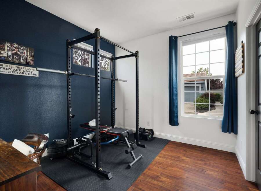 Elevate your fitness routine in this dedicated home gym space, featuring a robust power cage and adjustable bench for a comprehensive workout.