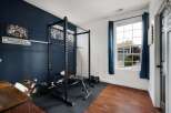 Elevate your fitness routine in this dedicated home gym space, featuring a robust power cage and adjustable bench for a comprehensive workout.