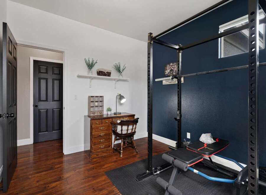 This versatile room offers a dedicated workspace with a charming wooden desk and lamp, perfect for productivity.