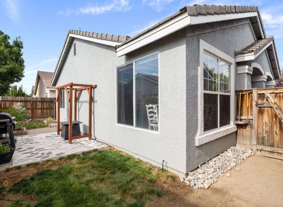 Enjoy outdoor living in this charming backyard featuring a spacious patio with a decorative rug, perfect for entertaining.