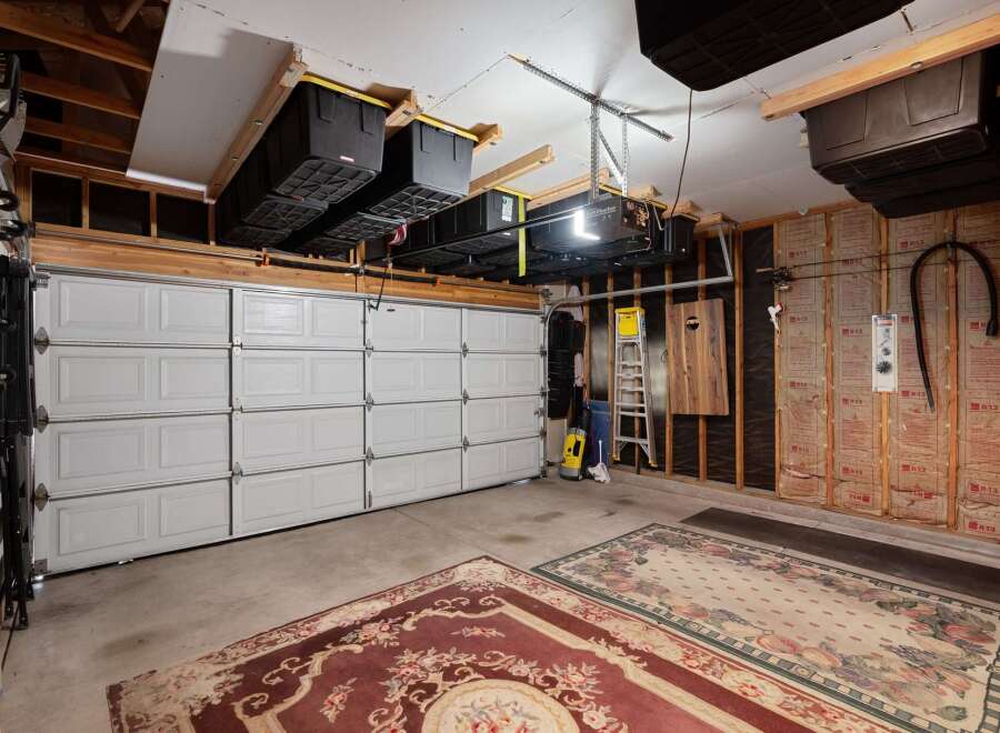 This spacious garage offers ample storage solutions with overhead shelving units holding multiple large bins, perfect for organizing your belongings.