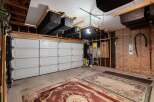 This spacious garage offers ample storage solutions with overhead shelving units holding multiple large bins, perfect for organizing your belongings.