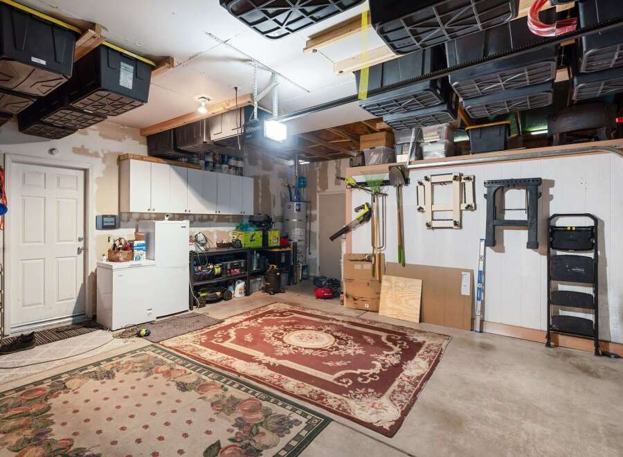 This spacious garage offers abundant storage solutions, including overhead bins and wall-mounted shelving, perfect for organizing tools and equipment.