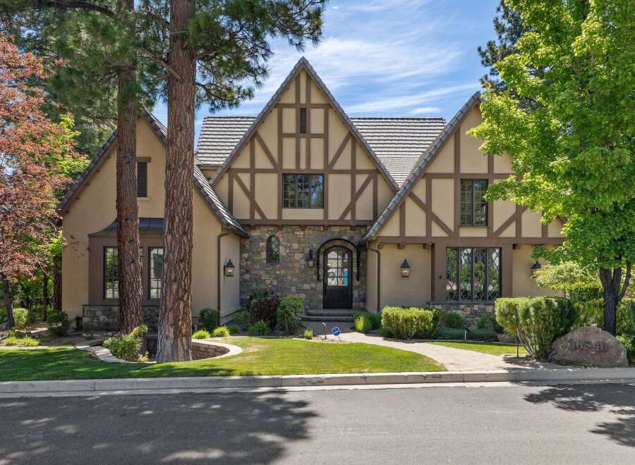 This stunning Tudor-style home boasts charming half-timbered accents and a stone-clad facade, creating a picturesque curb appeal.