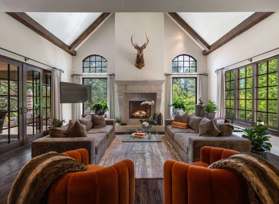 Experience luxurious living in this grand living room, featuring a stunning stone fireplace and vaulted ceilings with exposed wooden beams.
