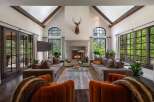 Experience luxurious living in this grand living room, featuring a stunning stone fireplace and vaulted ceilings with exposed wooden beams.