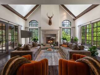 Experience luxurious living in this grand living room, featuring a stunning stone fireplace and vaulted ceilings with exposed wooden beams.