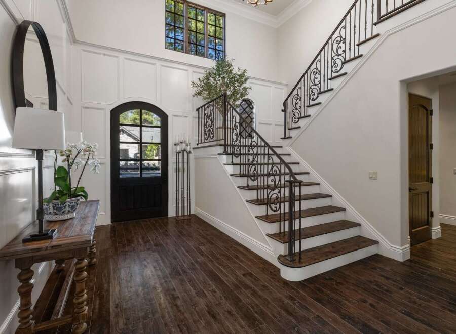 Step into this grand foyer featuring a stunning wrought-iron staircase and a charming arched doorway.