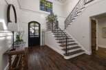 Step into this grand foyer featuring a stunning wrought-iron staircase and a charming arched doorway.