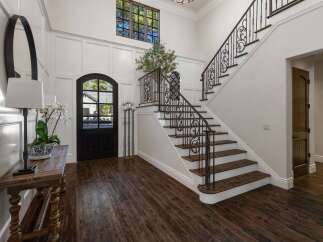 Step into this grand foyer featuring a stunning wrought-iron staircase and a charming arched doorway.