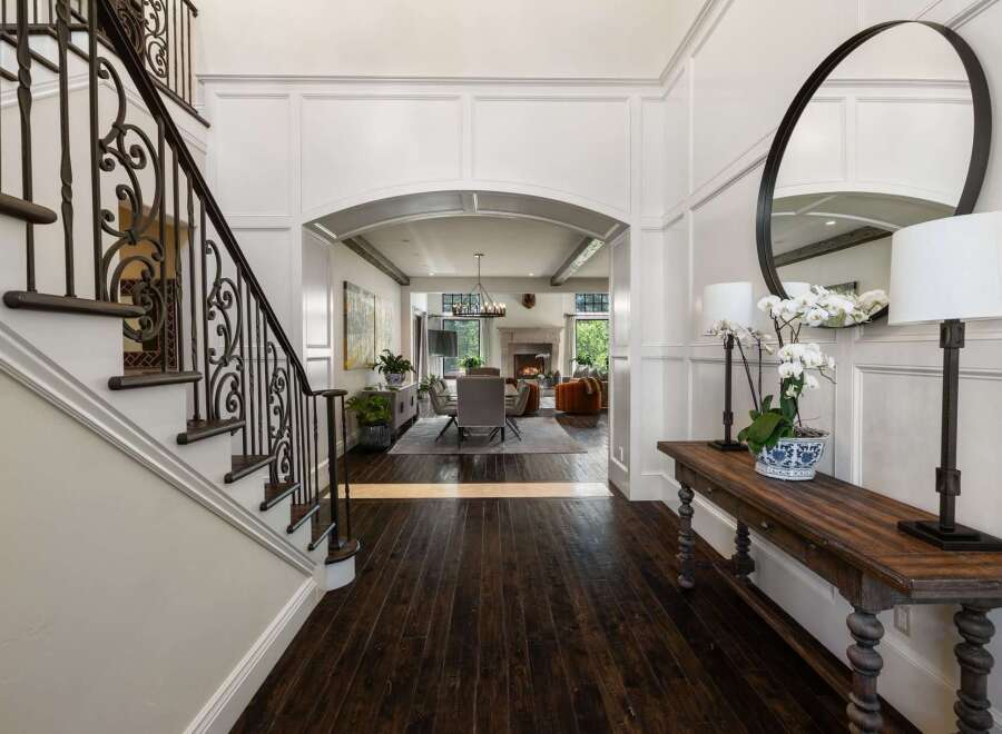 Step into a grand foyer featuring a stunning wrought iron staircase and elegant wainscoting.