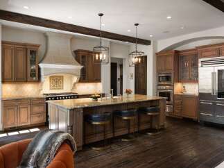 Experience luxury in this stunning gourmet kitchen, featuring custom wood cabinetry, a grand stone range hood, and a spacious granite island perfect for entertaining.