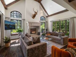 Experience luxurious mountain living in this stunning great room, featuring a grand stone fireplace and soaring vaulted ceilings with exposed wooden beams.