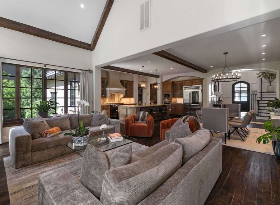 Experience luxurious open-concept living in this stunning home, featuring a spacious living area with plush seating and a large sectional, seamlessly flowing into a gourmet kitchen with custom cabinetry and a central island.