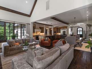Experience luxurious open-concept living in this stunning home, featuring a spacious living area with plush seating and a large sectional, seamlessly flowing into a gourmet kitchen with custom cabinetry and a central island.