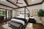 Experience luxurious comfort in this master bedroom, featuring a striking four-poster bed and elegant wooden beams on the ceiling.