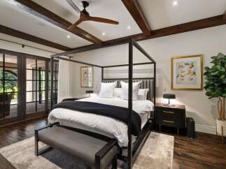 Experience luxurious comfort in this master bedroom, featuring a striking four-poster bed and elegant wooden beams on the ceiling.